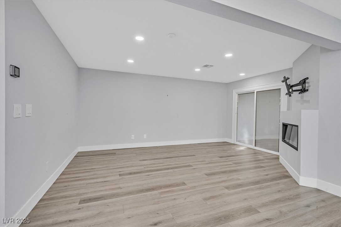 5421 Painted Mirage Road Las Vegas, NV 89149 - Photo 4 of 35 Unfurnished living room with recessed lighting, light wood-style flooring, baseboards, and a glass covered fireplace