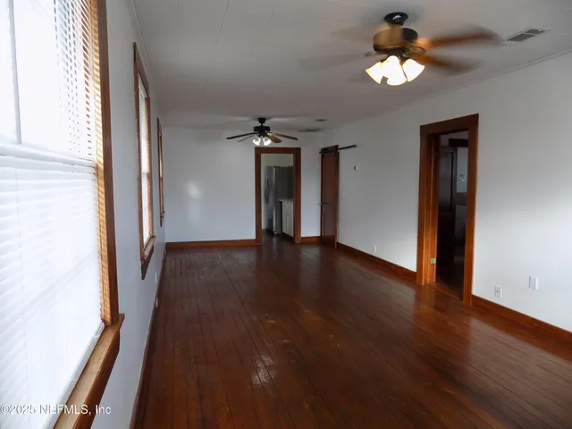 an empty room with wooden floor and windows