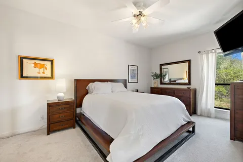 a bedroom with a bed a flat screen tv and a window