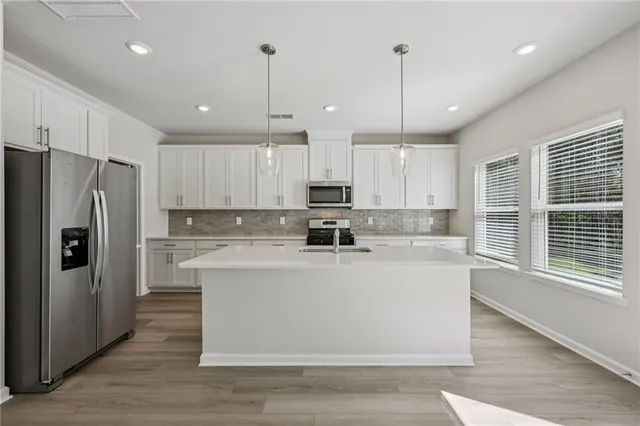 a large kitchen with stainless steel appliances granite countertop a refrigerator a stove a sink and a wooden floors