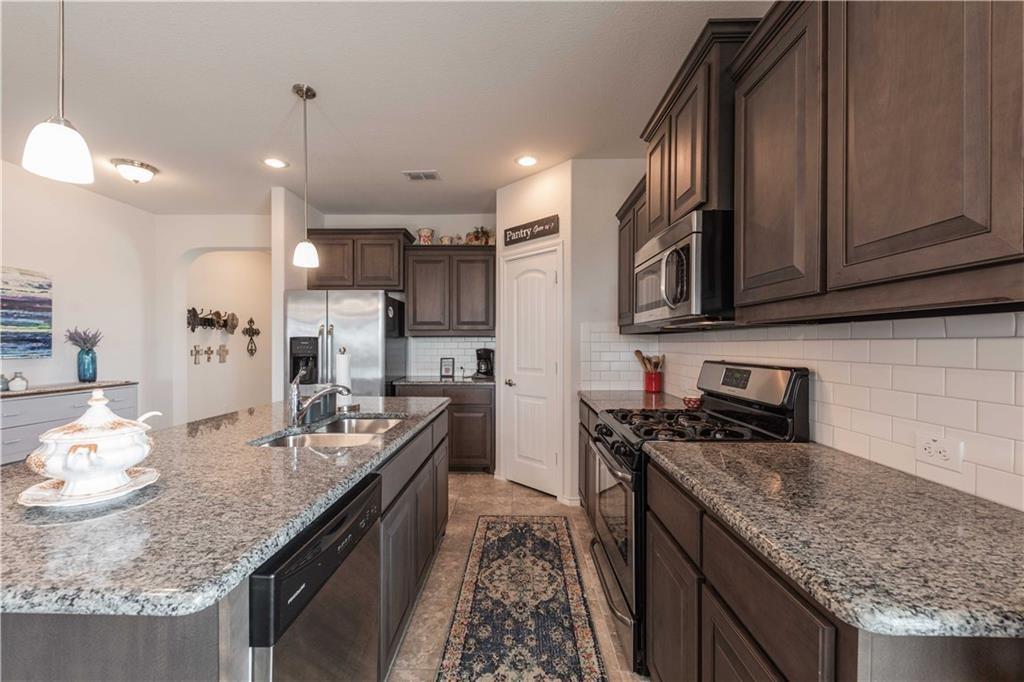 1716 Rio Penasco Road Fort Worth, TX 76052 - Photo 13 of 31 Kitchen featuring granite countertops, dark wood-finish cabinetry, stainless steel appliances, a subway tile backsplash, and recessed lighting