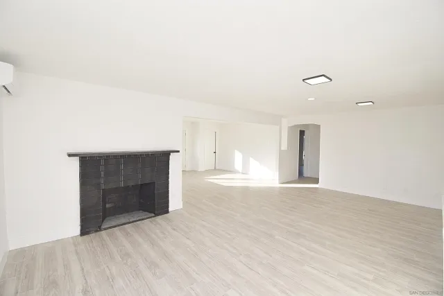 a view of empty room with wooden floor and fireplace