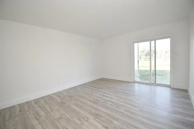 a view of an empty room with wooden floor and window