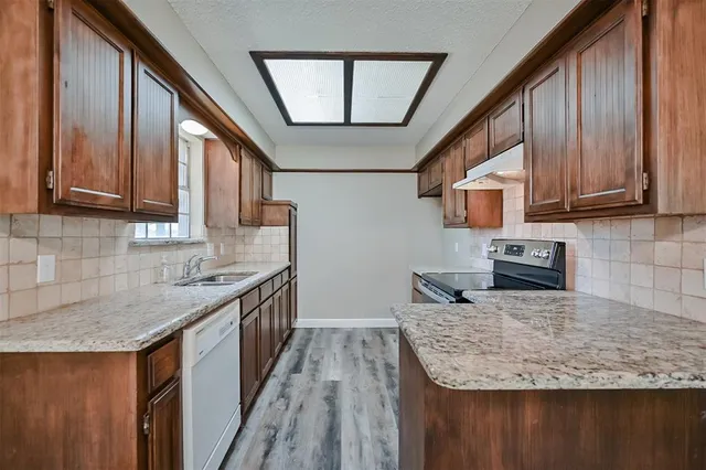 a kitchen with granite countertop a sink a stove and a microwave oven