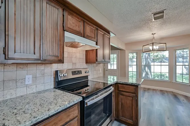 a kitchen with stainless steel appliances granite countertop wooden cabinets a stove top oven a sink and dishwasher
