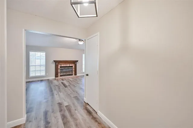 an empty room with wooden floor fireplace and windows