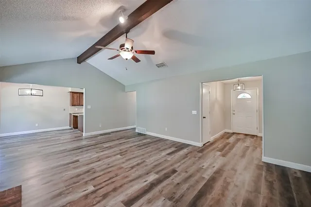 a view of an empty room with window and wooden floor