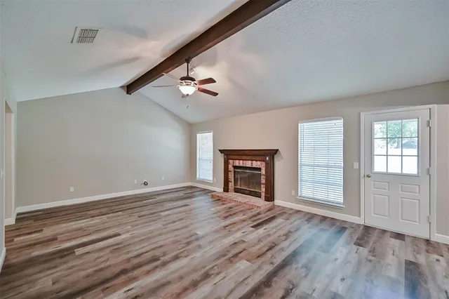 a view of empty room with wooden floor and fireplace