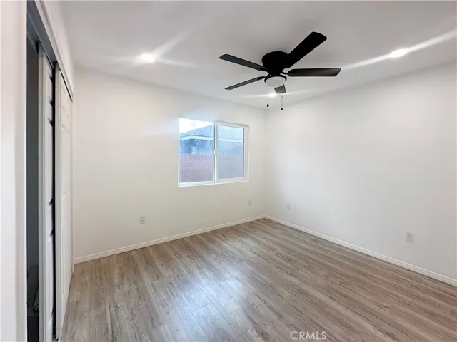 an empty room with wooden floor a ceiling fan and windows