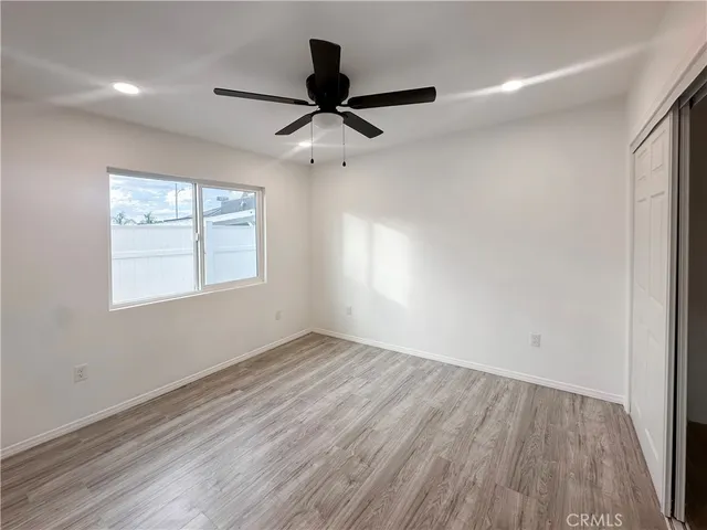 an empty room with wooden floor ceiling fan and windows