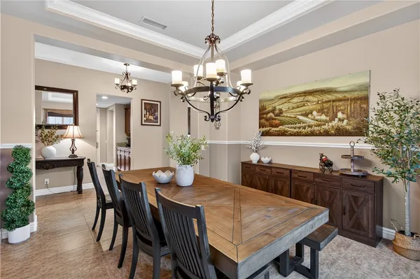 a dining room with wooden floor a chandelier a wooden table and chairs