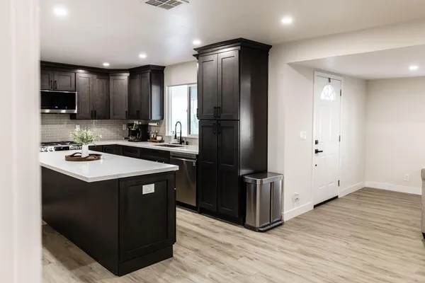 a kitchen with kitchen island stainless steel appliances a sink cabinets and a counter top space