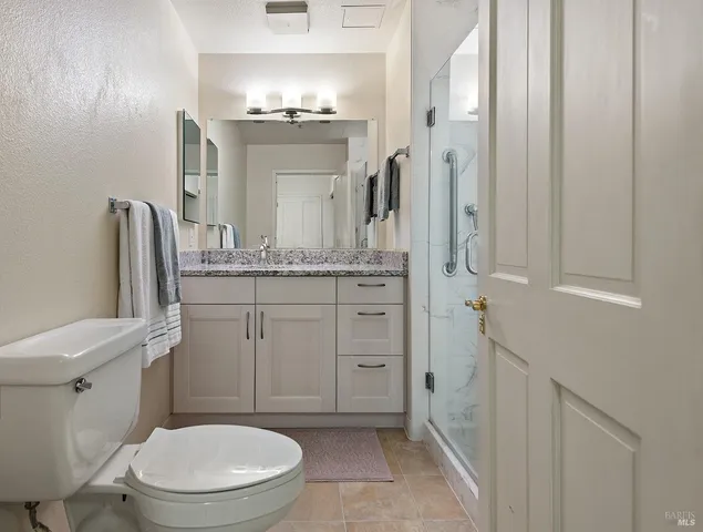a bathroom with a granite countertop toilet sink and mirror