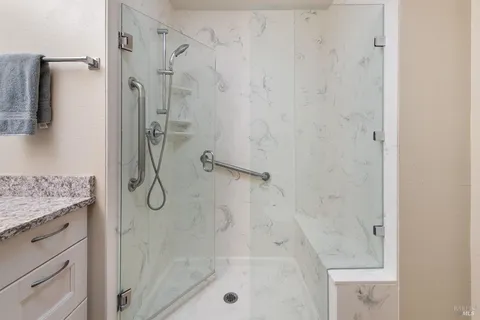 a bathroom with a granite countertop shower a mirror and a sink