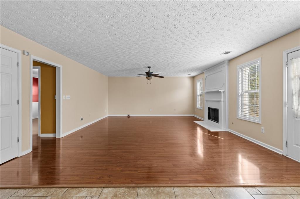 2760 Rusticwood Drive Southwest Snellville, GA 30078 - Photo 14 of 48 an empty room with wooden floor chandelier fan and windows