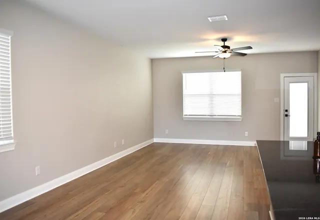 a view of an empty room with wooden floor and a window