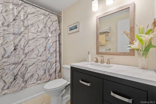 a bathroom with a granite countertop sink and a toilet