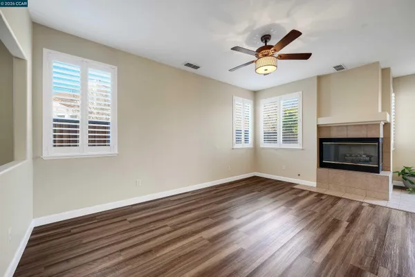 an empty room with wooden floor a ceiling fan and windows