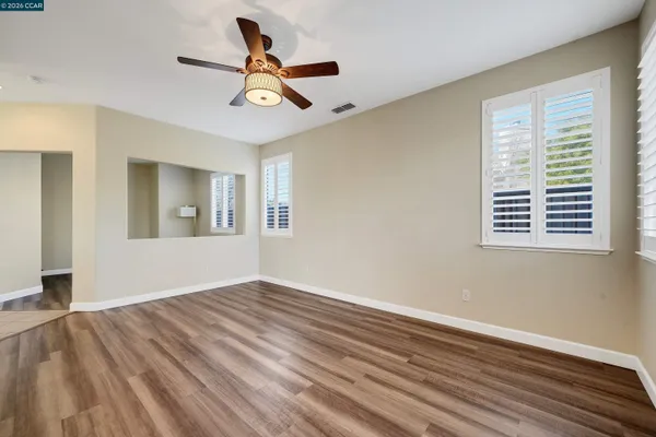 a view of empty room with wooden floor and fan