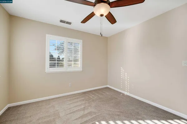 an empty room with a window and a fan