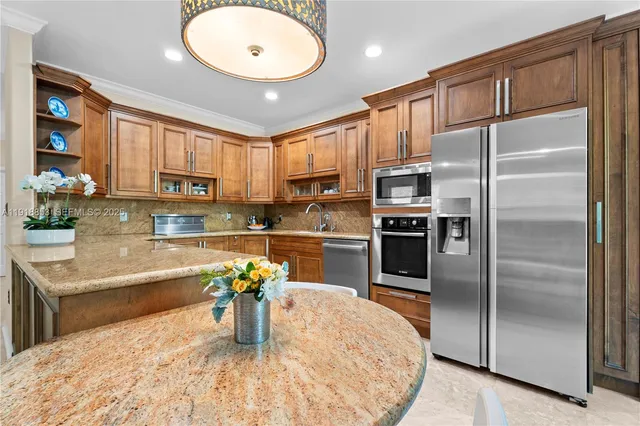 a kitchen with stainless steel appliances granite countertop a refrigerator a stove and a sink