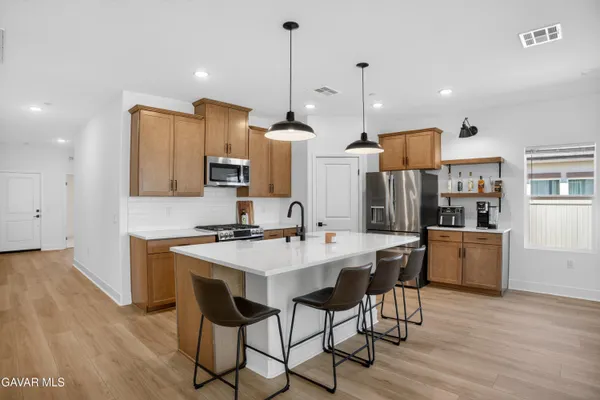 a kitchen with stainless steel appliances kitchen island granite countertop a sink a stove a refrigerator and island with wooden floor