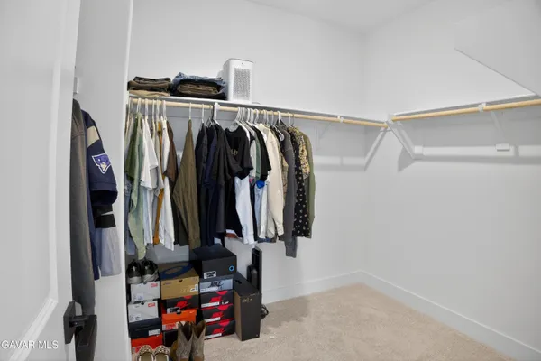 a view of walk in closet with clothes and shoes