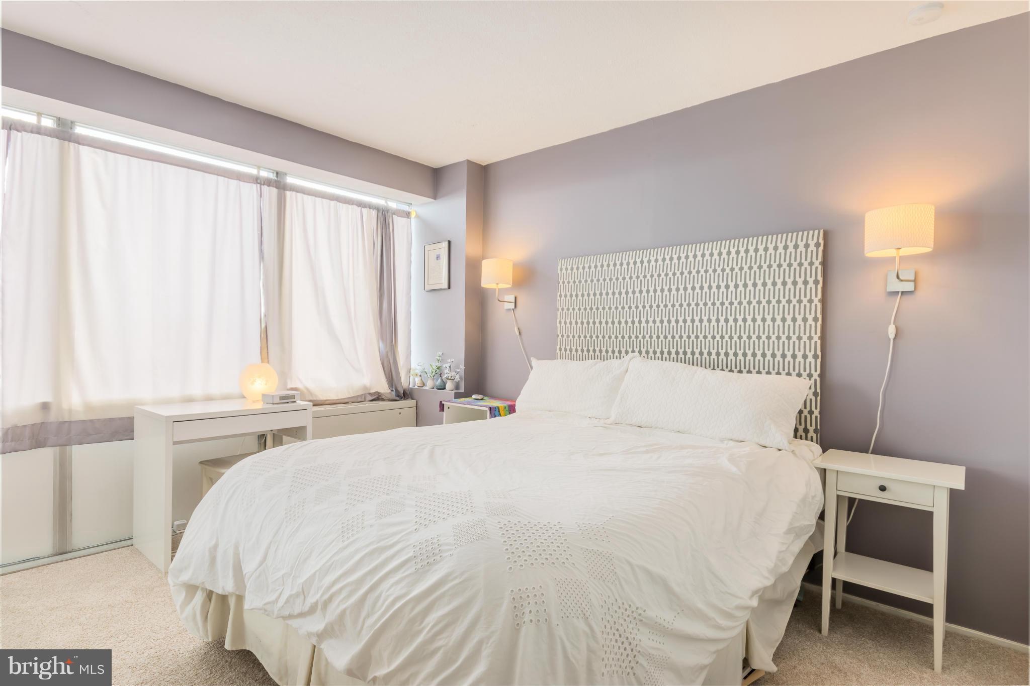 1301 Delaware Avenue Southwest, Unit N816 Washington, DC 20024 - Photo 11 of 20 a large bed sitting in a bedroom next to a window and a chair