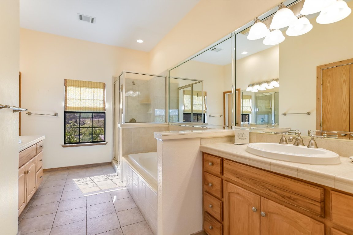 116 Courtside Way Spicewood, TX 78669 - Photo 19 of 40 a spacious bathroom with a sink a mirror and a bathtub