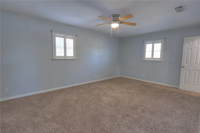an empty room with window and chandelier fan