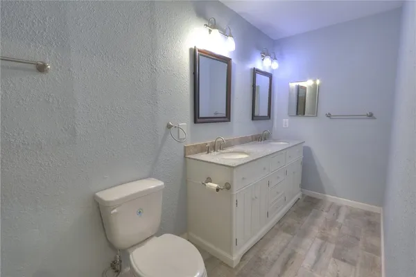 a bathroom with a granite countertop sink toilet and mirror