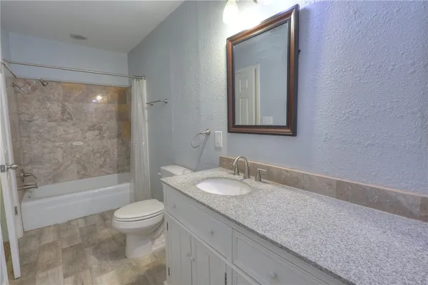 a bathroom with a granite countertop sink a toilet and shower