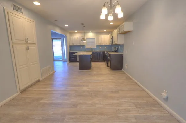 a open kitchen with a sink dishwasher a kitchen island a stove and a refrigerator with wooden floor