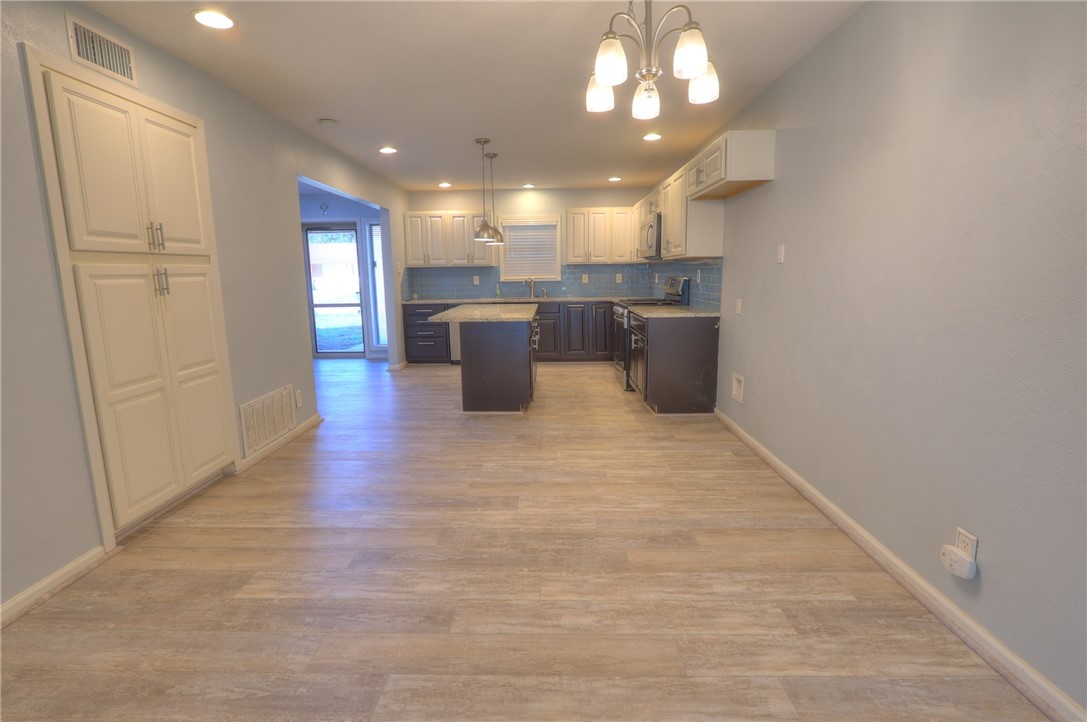 3141 Baybrook Drive Corpus Christi, TX 78418 - Photo 10 of 32 a open kitchen with a sink dishwasher a kitchen island a stove and a refrigerator with wooden floor