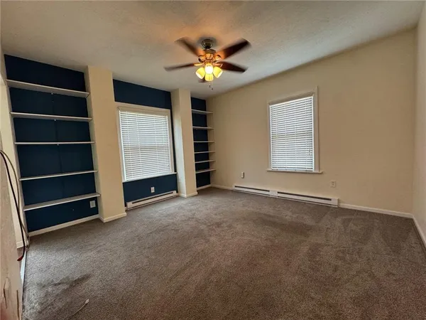 a view of an empty room with a window and a ceiling fan