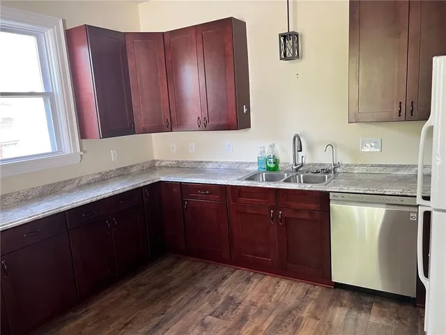 a kitchen with stainless steel appliances granite countertop wooden cabinets a sink and dishwasher with wooden floor