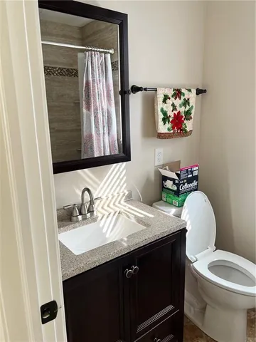 a bathroom with a granite countertop toilet sink and mirror
