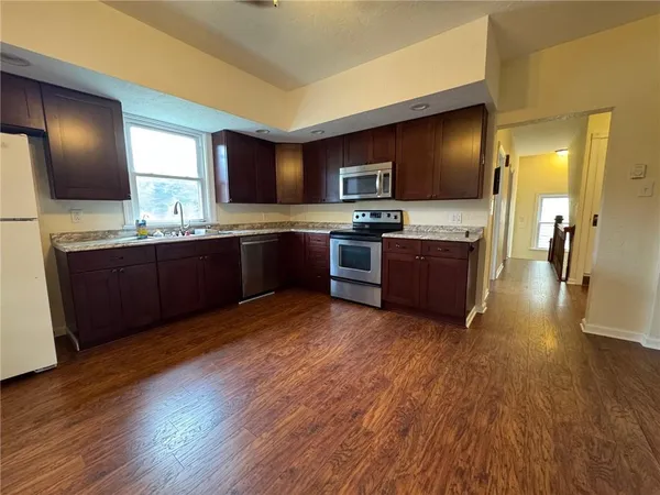 a large kitchen with wooden floors and stainless steel appliances