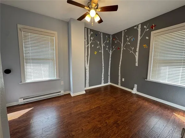 a view of an empty room with window and wooden floor
