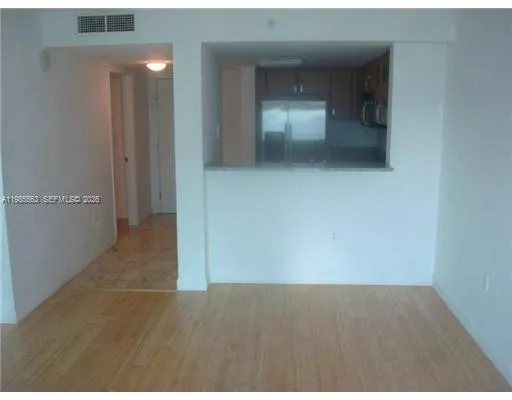 a view of an empty room with wooden floor and windows
