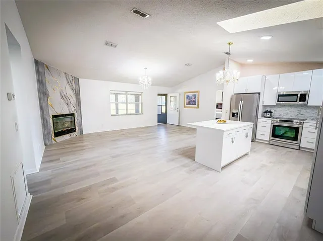 a large white kitchen with a stove a sink a refrigerator and a fireplace