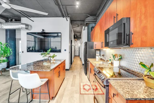 a kitchen with stainless steel appliances granite countertop a sink and a refrigerator