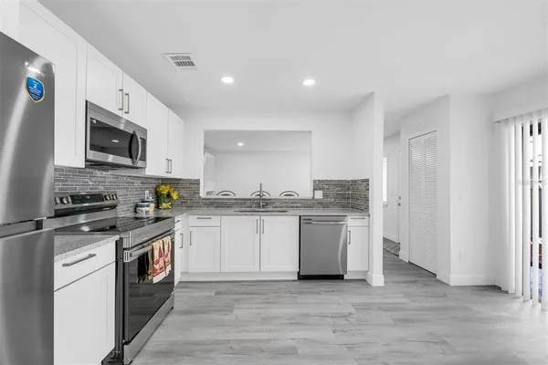 a kitchen with a refrigerator a sink dishwasher a stove and white cabinets with wooden floor