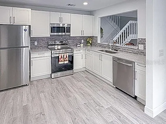 a kitchen with a refrigerator stove and white cabinets