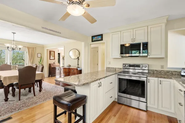 a large kitchen with stainless steel appliances granite countertop a stove and a view of living room