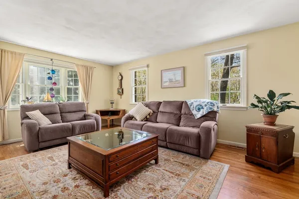 a living room with furniture large window and wooden floor