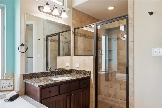 a bathroom with a granite countertop sink a mirror and a shower