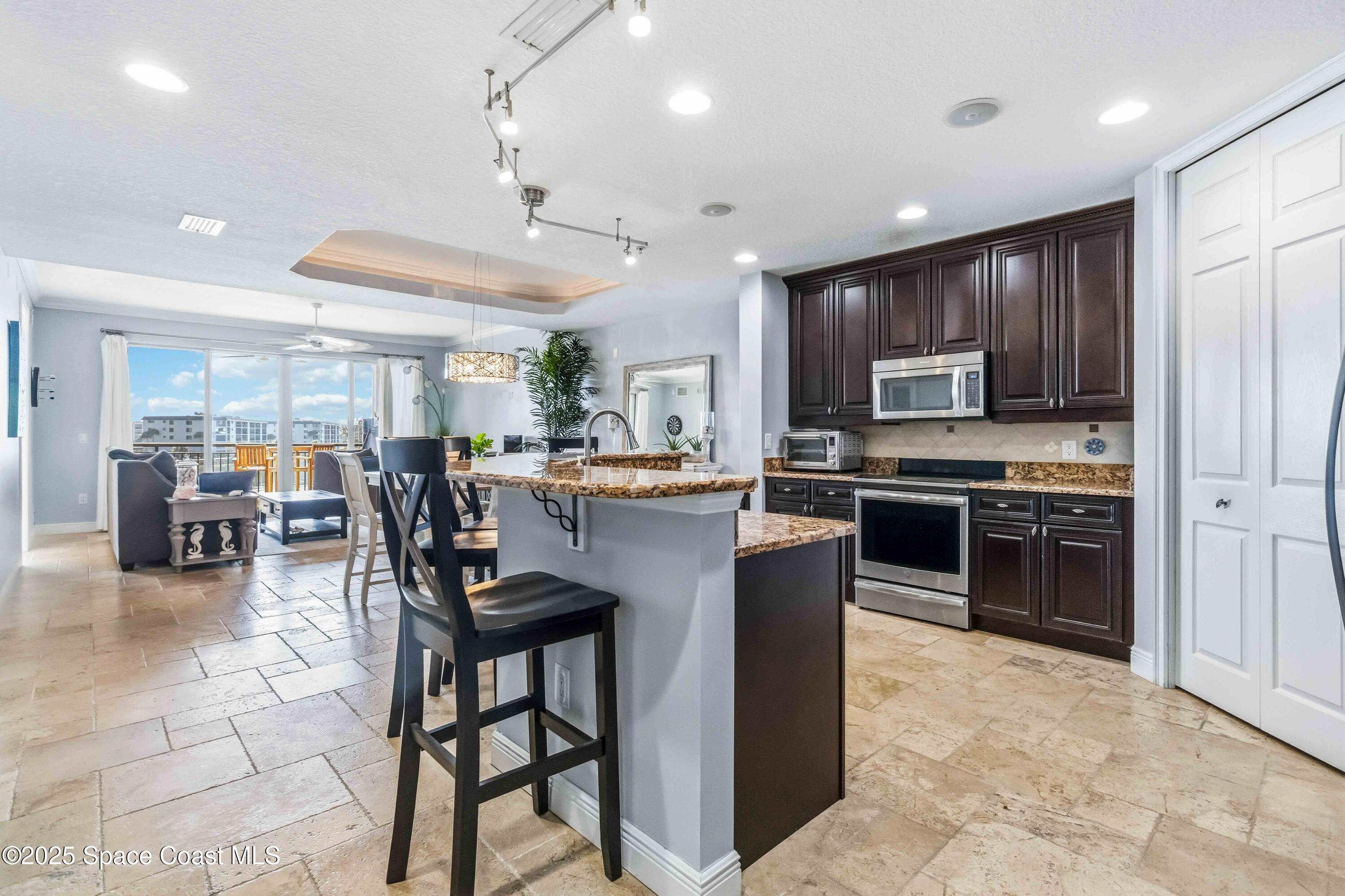 4125 West End Road, Unit 306 Cocoa Beach, FL 32931 - Photo 5 of 51 a kitchen with stainless steel appliances kitchen island granite countertop a stove a sink a refrigerator a dining table and chairs