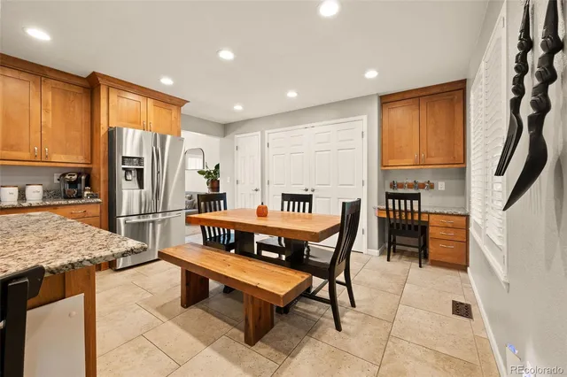 a kitchen with stainless steel appliances kitchen island granite countertop a refrigerator a stove a sink a dining table and chairs with wooden floor