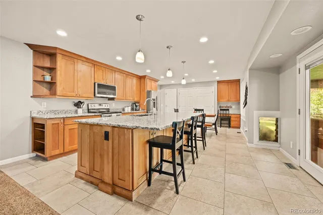 a kitchen with stainless steel appliances kitchen island granite countertop a stove a sink a dining table and chairs